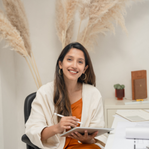 Professional digital marketer smiling at desk while working on a tablet, representing Suhani Bhardwaj’s creative and strategic approach to digital marketing and brand growth.